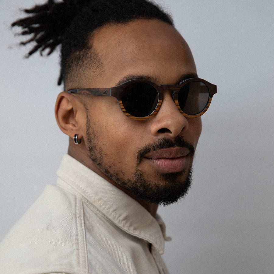 Black man wearing eco friendly round wooden sunglasses with polarised lenses