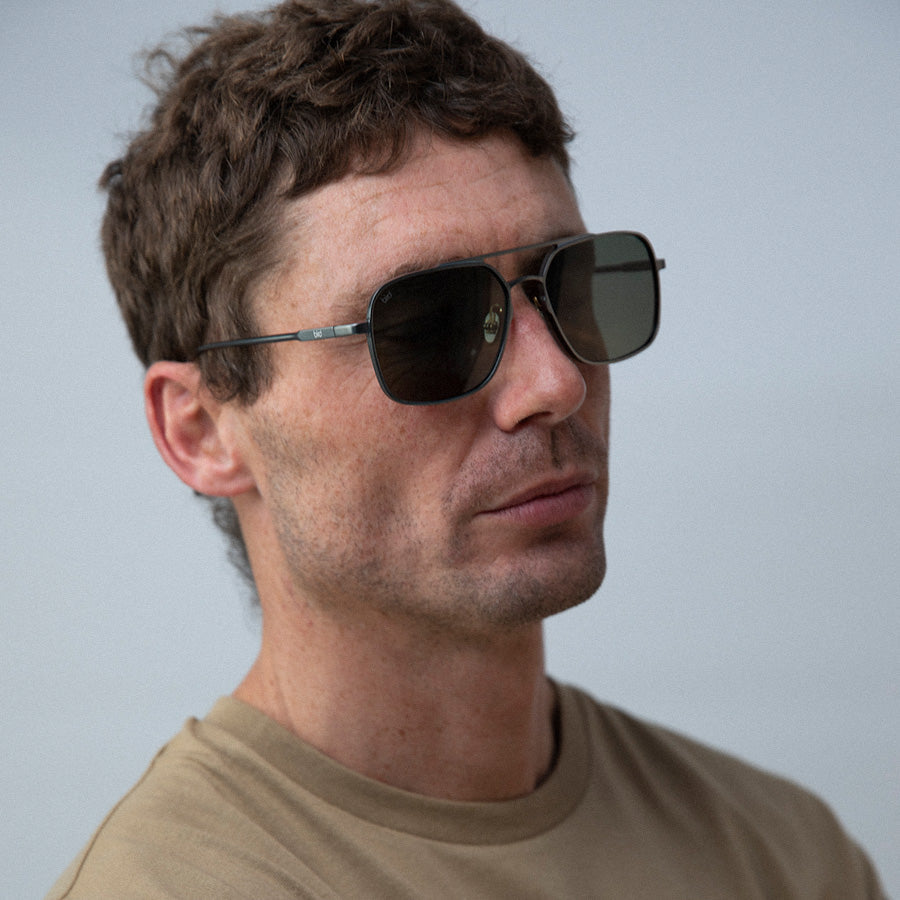 Man wearing large square metal sunglasses facing sideways