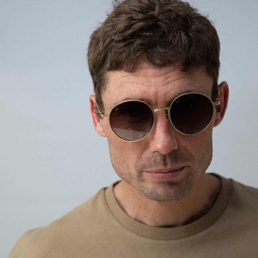 Man wearinground sunglasses with gold frame and grey lenses