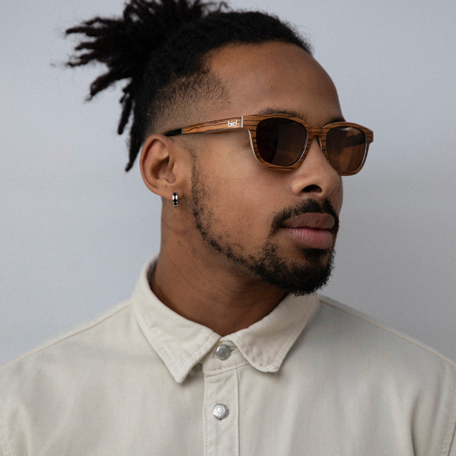 Black man wearingEco conscious wooden sunglasses with light coloured wood facing sideways