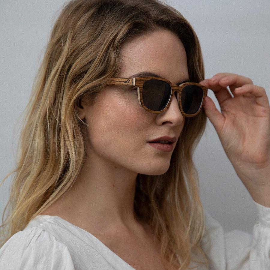 Woman wearingEco conscious wooden sunglasses with light coloured wood looking sideways