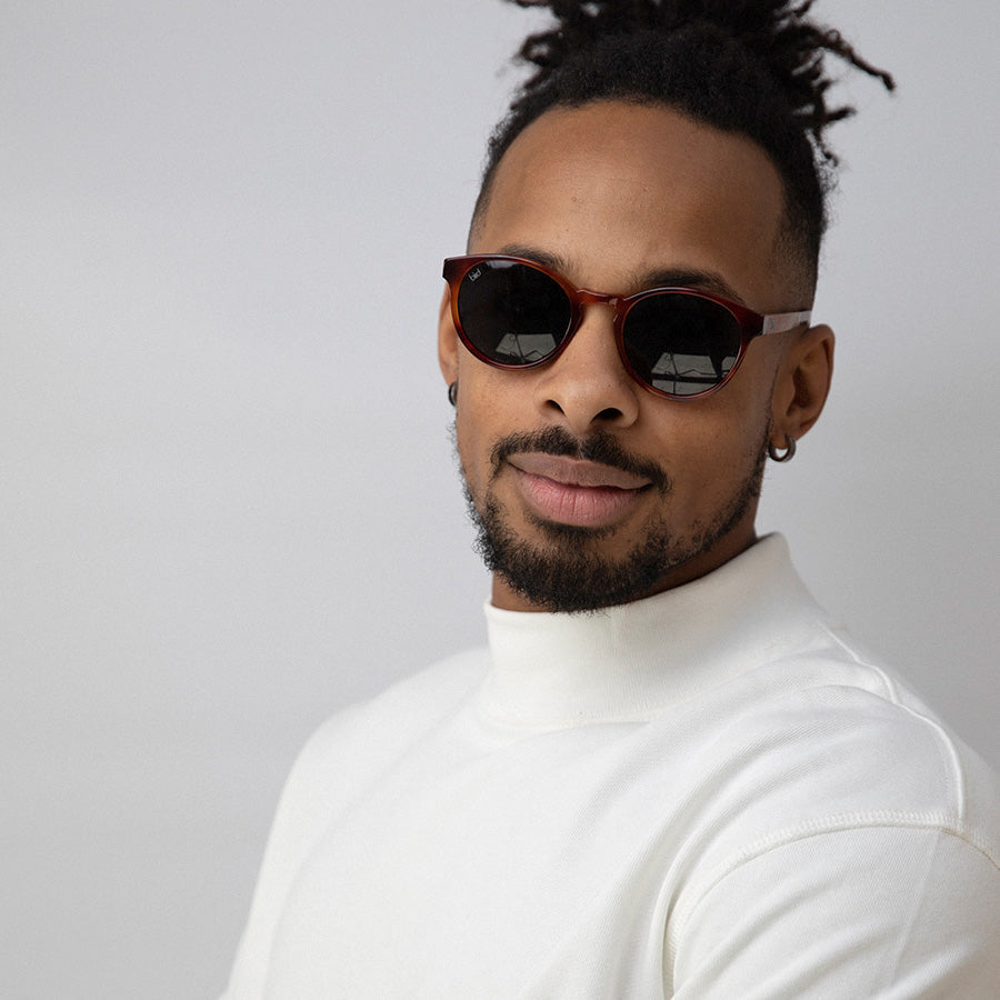 Black man wearing red bio acetate sunglasses with grey lenses