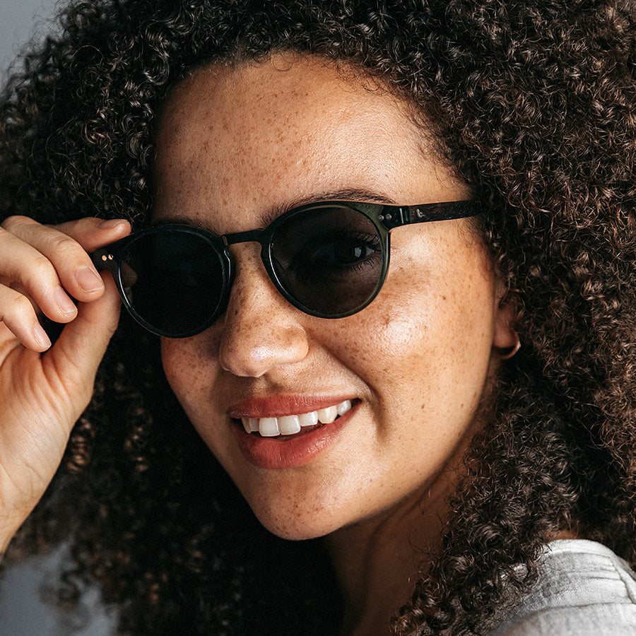 Black woman wearing olive green sunglasses 